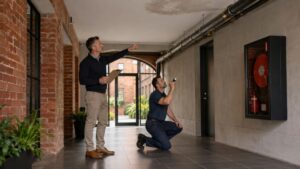 Technician and building manager inspecting a shared pipe in a converted warehouse apartment building in Richmond